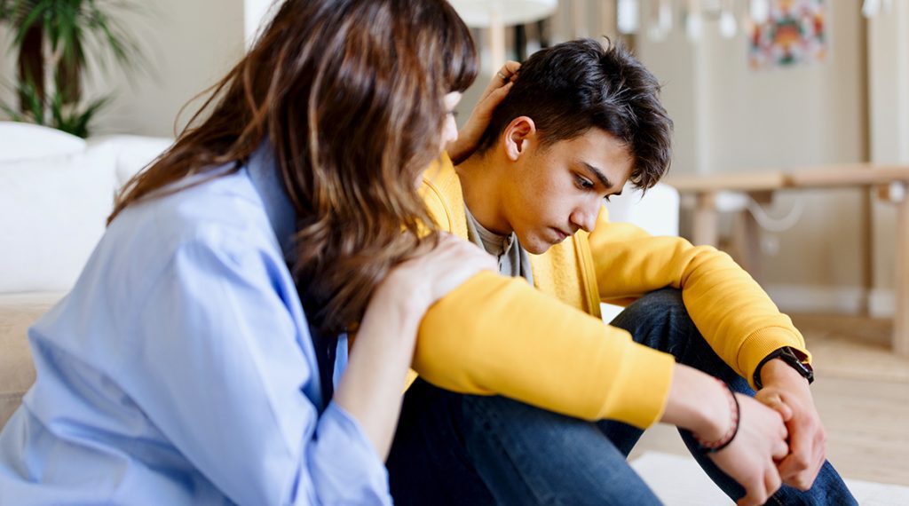 Mother consoling teen boy