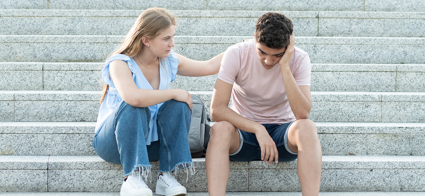 Girl comforting boy on staircase.