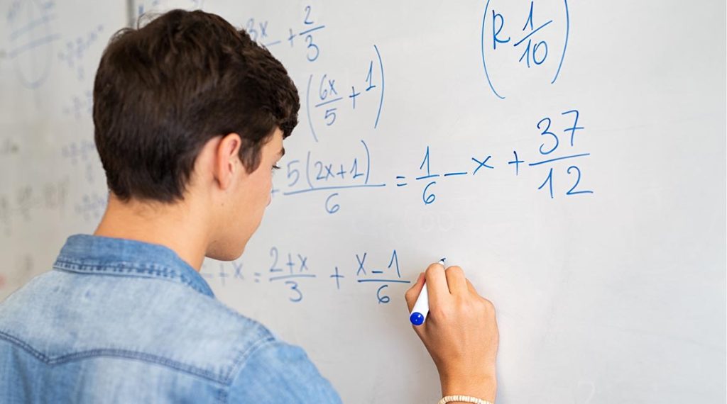 College student solving math equation on white board