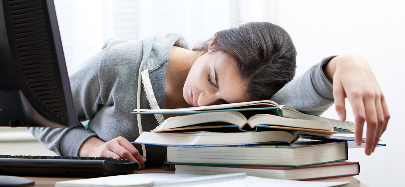 teen laying on books exhausted