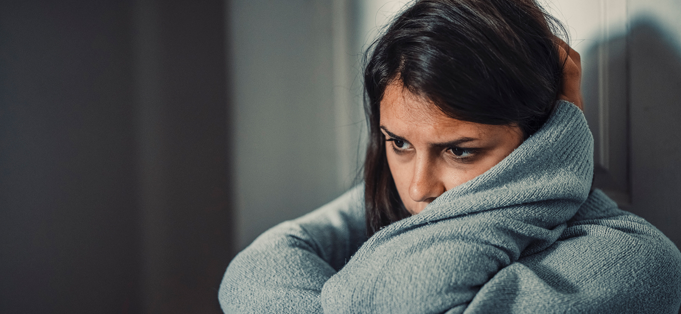Stress and sad teen girl curled up against a wall